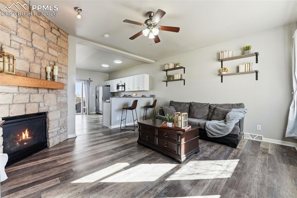 6535 Gelbvieh Road Peyton, CO 80831 - Photo 4 of 41 Living area with a ceiling fan, dark wood-type flooring, and a stone fireplace