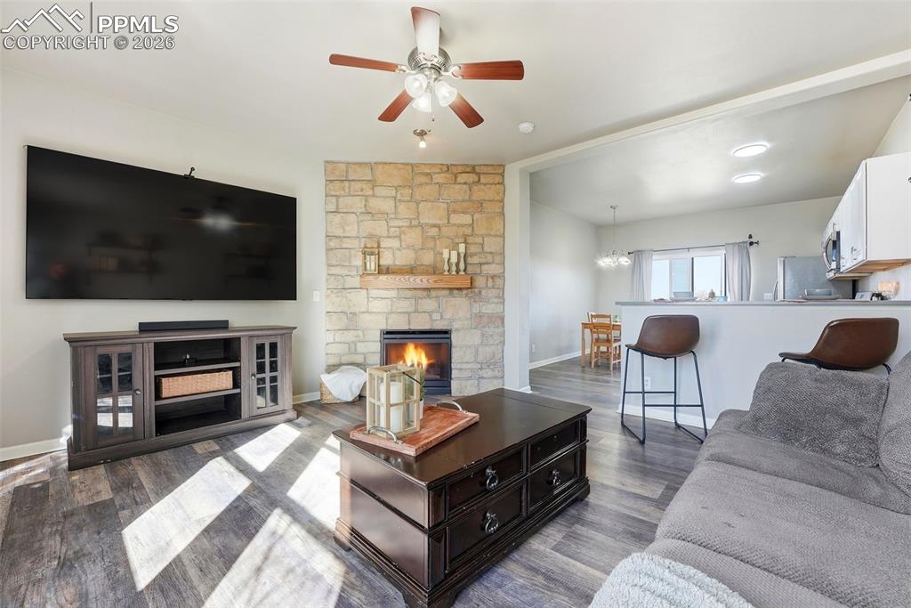 6535 Gelbvieh Road Peyton, CO 80831 - Photo 5 of 41 Living room with ceiling fan, a stone fireplace, and dark wood-type flooring
