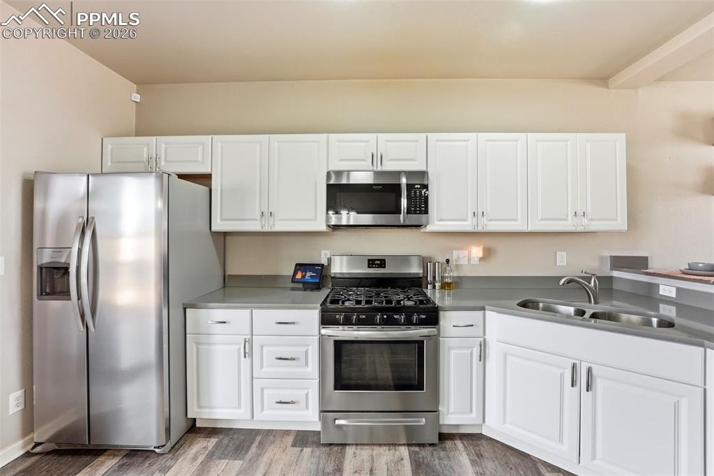 6535 Gelbvieh Road Peyton, CO 80831 - Photo 9 of 41 Kitchen featuring stainless steel appliances, white cabinets, and light wood finished floors