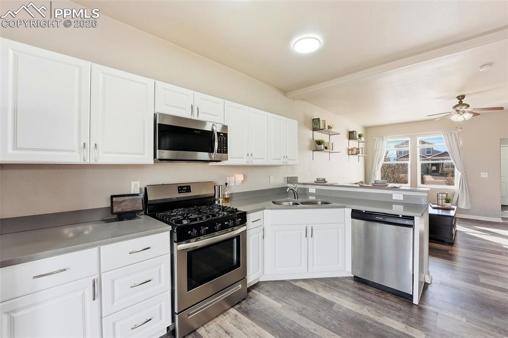 6535 Gelbvieh Road Peyton, CO 80831 - Photo 10 of 41 Kitchen with stainless steel appliances, white cabinets, and a peninsula