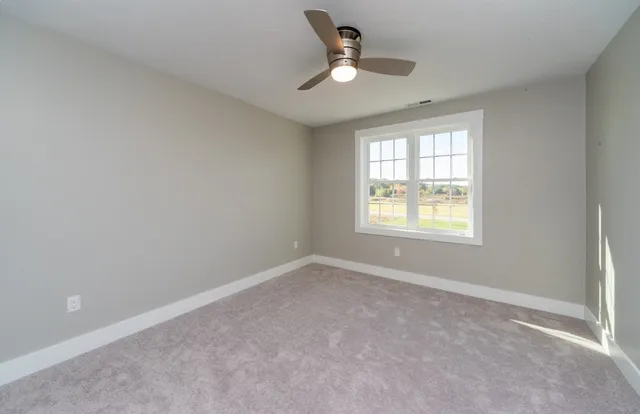 a view of an empty room and chandelier fan