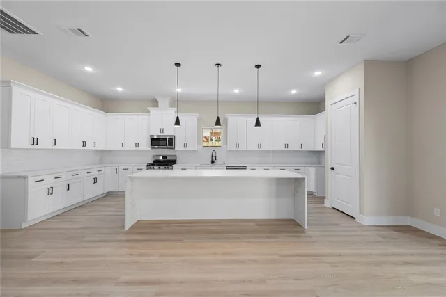 a view of kitchen with granite countertop a white stove top oven and white cabinets