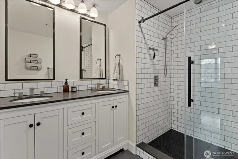 a bathroom with a double vanity sink a mirror and shower