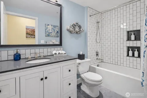 a bathroom with a granite countertop toilet sink and mirror