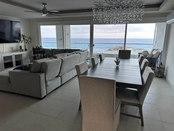 a living room with couches chairs and a large window with kitchen view