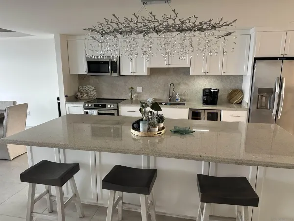 a kitchen with stainless steel appliances granite countertop a table chairs in it and a window