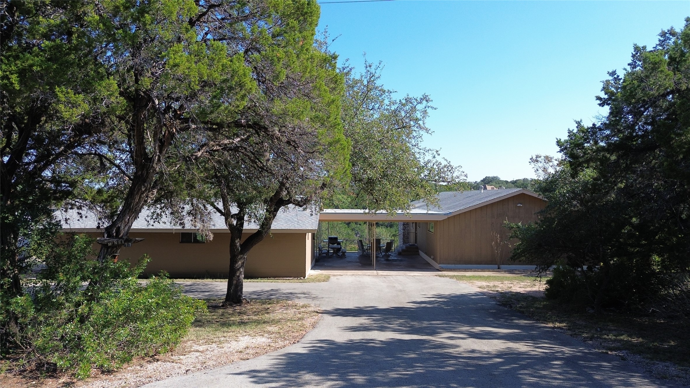 3807 Boat Dock Road Lago Vista, TX 78645 - Photo 23 of 37 A private driveway leads to a secluded home nestled among mature trees, boasting a covered outdoor area perfect for relaxation.