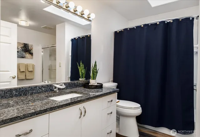 a bathroom with a granite countertop sink toilet and shower