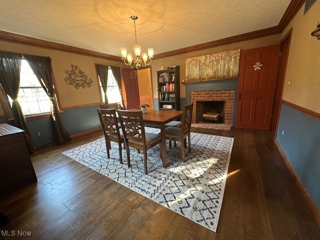 1975 Warner Road Southeast Hubbard, OH 44425 - Photo 19 of 23 Dining space featuring crown molding, a brick fireplace, dark wood-style floors, a chandelier, and wainscoting
