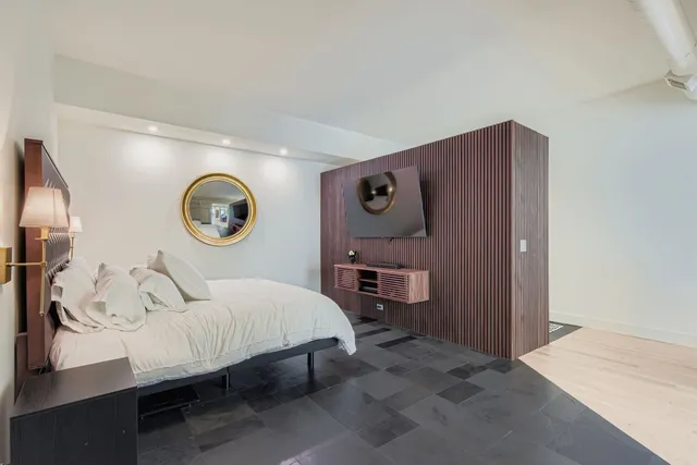 a bedroom with a bed and a lamp on dresser