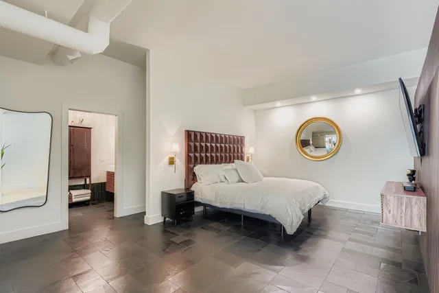 a spacious bedroom with a bed and a large mirror