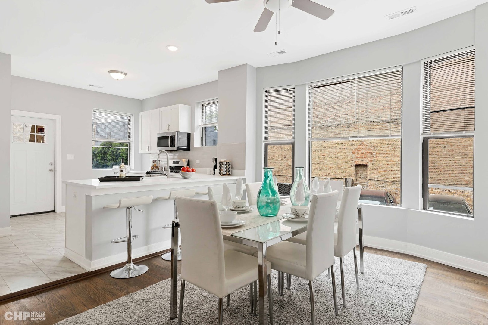 416 East 44th Street, Unit 1 Chicago, IL 60653 - Photo 6 of 25 a kitchen with kitchen island granite countertop a dining table chairs and white cabinets next to a window