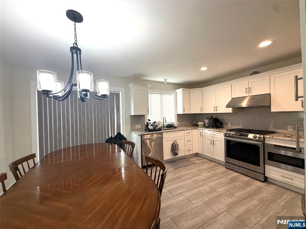 43 Jackson Avenue, Unit 1 Hackensack, NJ 07601 - Photo 4 of 14 a kitchen with granite countertop a stove a sink dishwasher a refrigerator and white cabinets with wooden floor