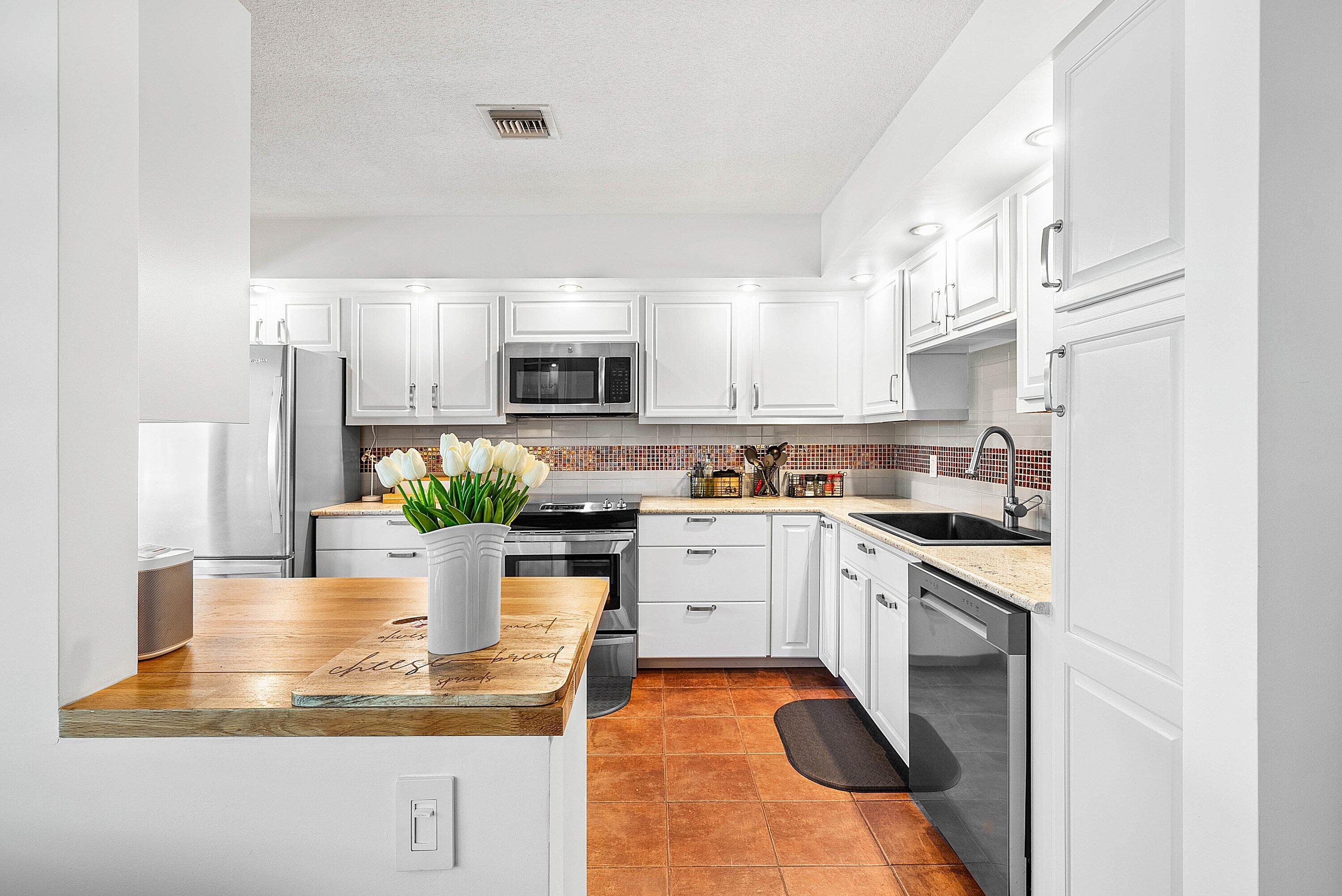 11126 Quail Covey Road, Unit MOCKINGBIRD Boynton Beach, FL 33436 - Photo 3 of 58 a kitchen with kitchen island granite countertop a stove a sink and a microwave
