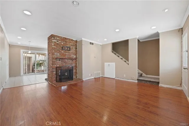 a view of empty room with wooden floor and fireplace