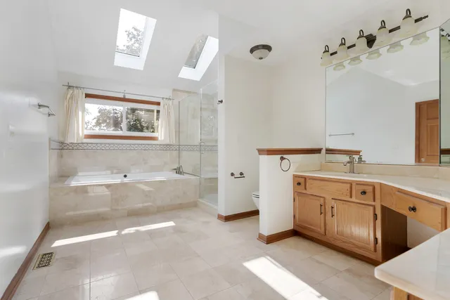 a spacious bathroom with a tub sink and mirror