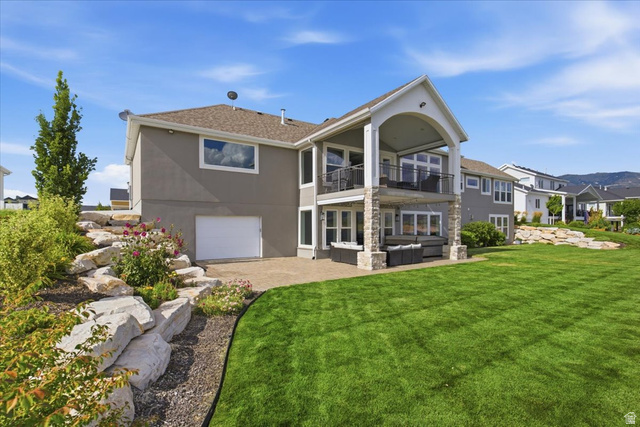 21 Pier Place Tooele, UT 84074 - Photo 87 of 112 Expansive rear exterior featuring a large green lawn, a covered upper-level balcony with metal railings, and a lower-level covered patio