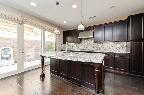 a kitchen with kitchen island granite countertop wooden floors and white cabinets