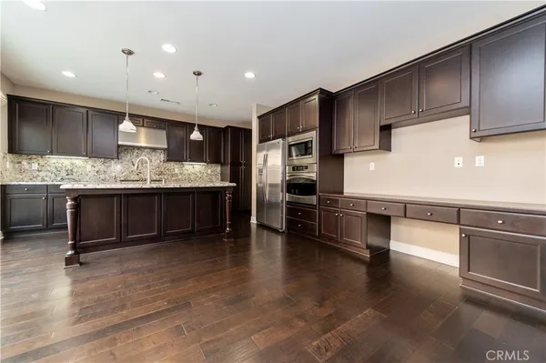 a kitchen with stainless steel appliances kitchen island granite countertop a stove a sink and a refrigerator