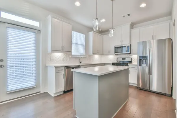 a kitchen with kitchen island granite countertop a sink a counter space stainless steel appliances and cabinets
