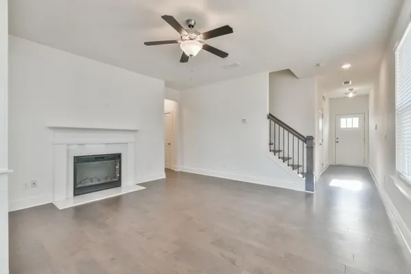 a view of an empty room with chandelier fan and fire place