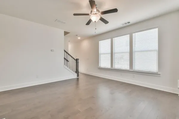 an empty room with windows and fan