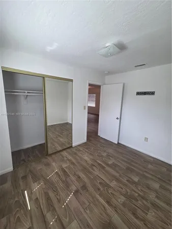 a view of an empty room with wooden floor and closet