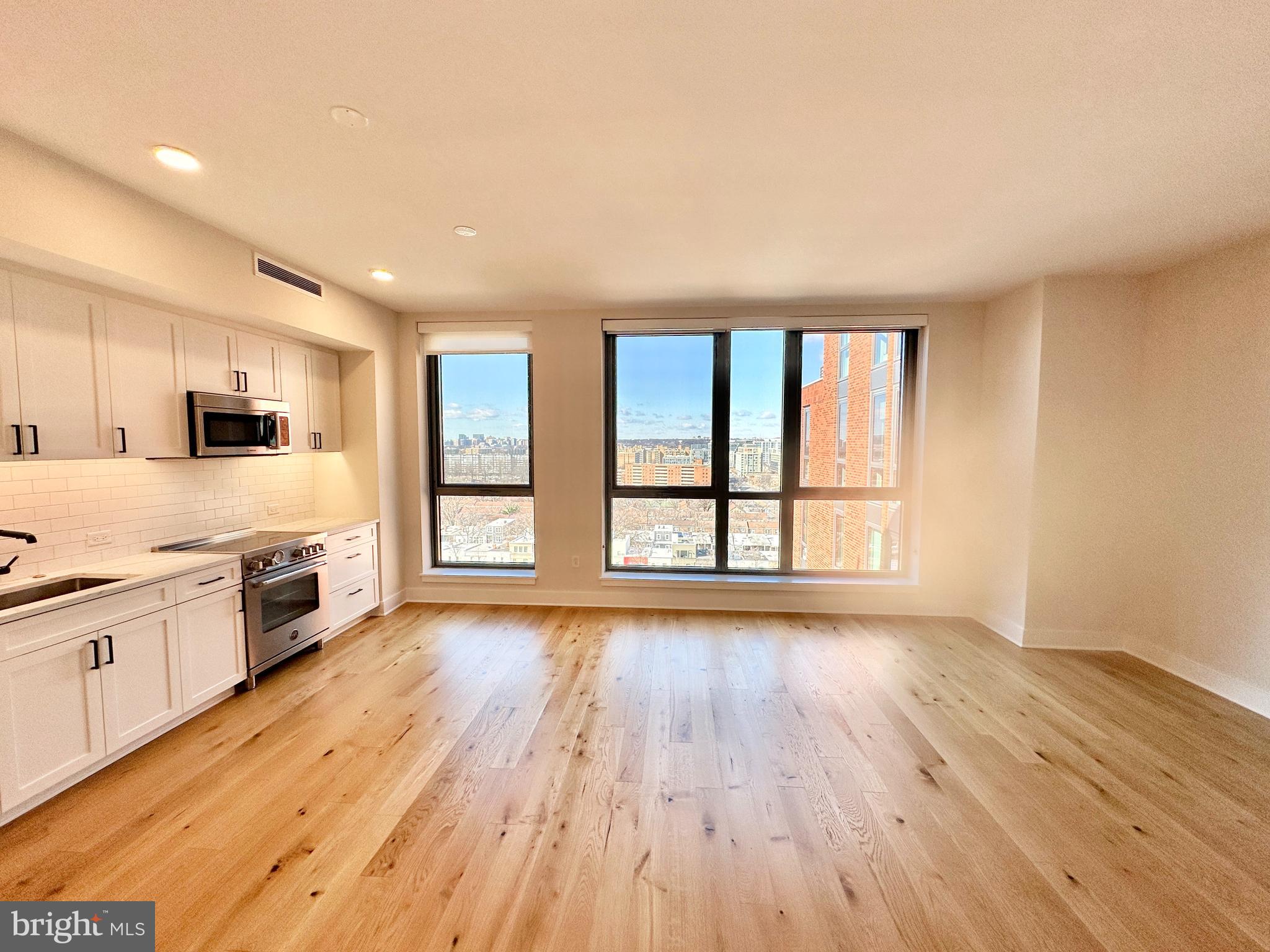 1211 Van Street Southeast, Unit 1201 Washington, DC 20003 - Photo 5 of 58 a large kitchen with kitchen island wooden floors and stainless steel appliances