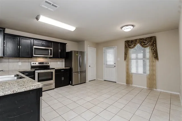 a kitchen with stainless steel appliances granite countertop a refrigerator a stove top oven a sink and dishwasher