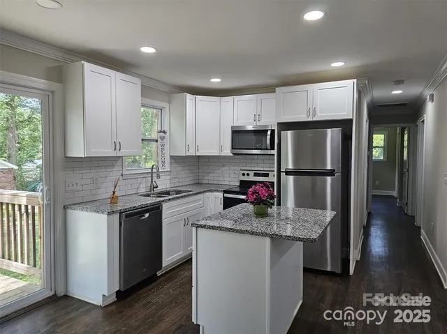 a kitchen with kitchen island granite countertop appliances cabinets a sink and a counter top space
