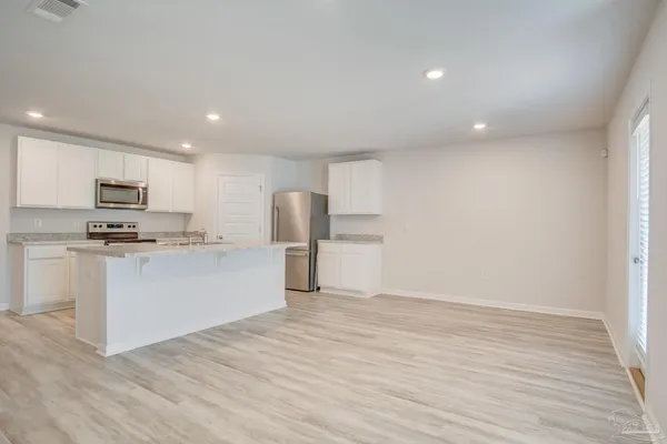 an empty room with wooden floor ceiling fan and windows