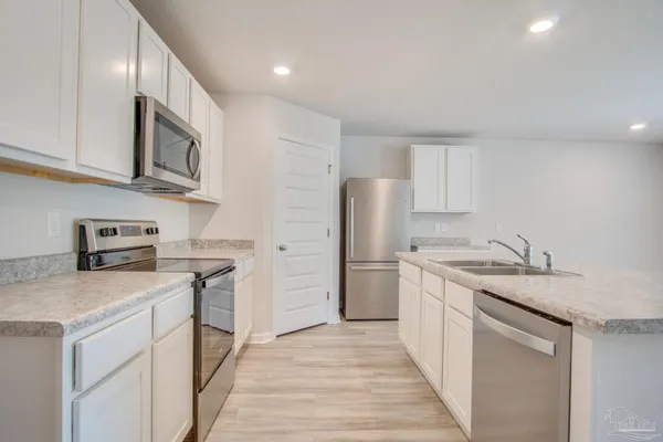 a kitchen with kitchen island white cabinets and stainless steel appliances
