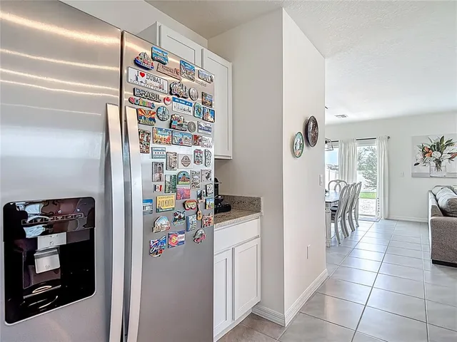 a kitchen with stainless steel appliances granite countertop a refrigerator a stove a sink a dining table and chairs