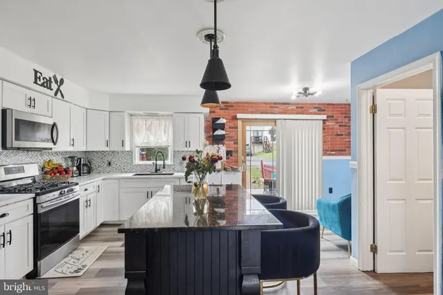 a kitchen with stainless steel appliances a dining table chairs refrigerator and sink
