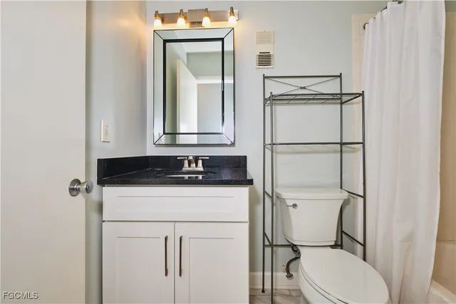 a bathroom with a toilet sink vanity and mirror