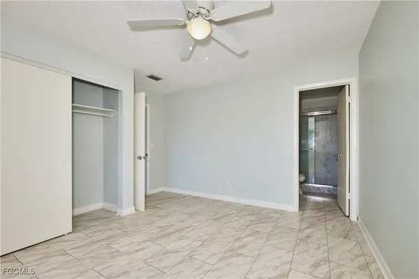 an empty room with closet and a chandelier fan