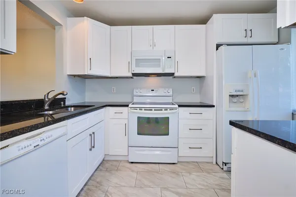 a kitchen with white cabinets and white appliances