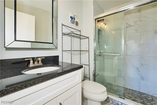 a bathroom with a granite countertop sink a mirror and a toilet