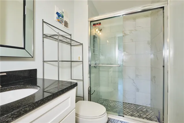 a bathroom with a granite countertop sink toilet and shower