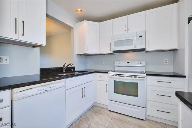 a kitchen with white cabinets and white appliances