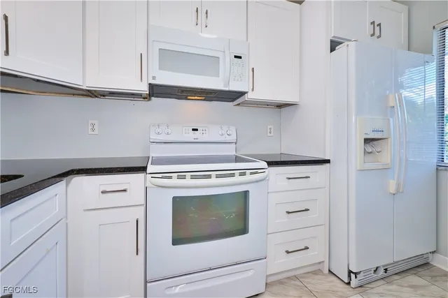a kitchen with white cabinets and white appliances