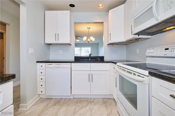 a kitchen with white cabinets and white appliances