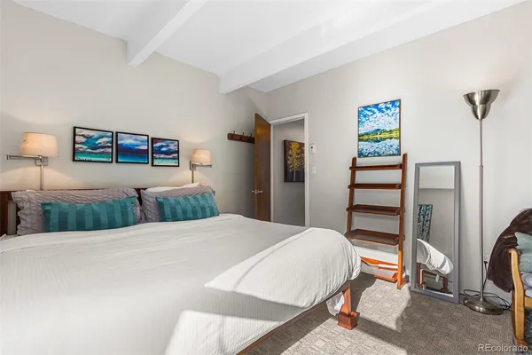 a bedroom with a bed a dresser and painting on the wall
