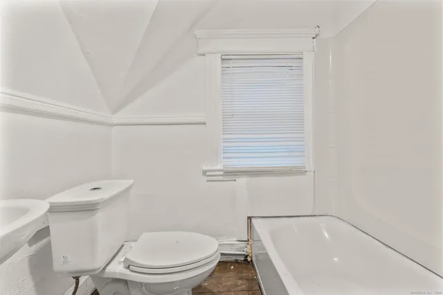 a white toilet sitting next to a bath tub