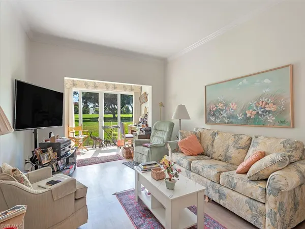 a living room with furniture floor to ceiling window and a flat screen tv