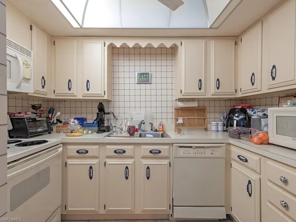 a kitchen with white cabinets and appliances