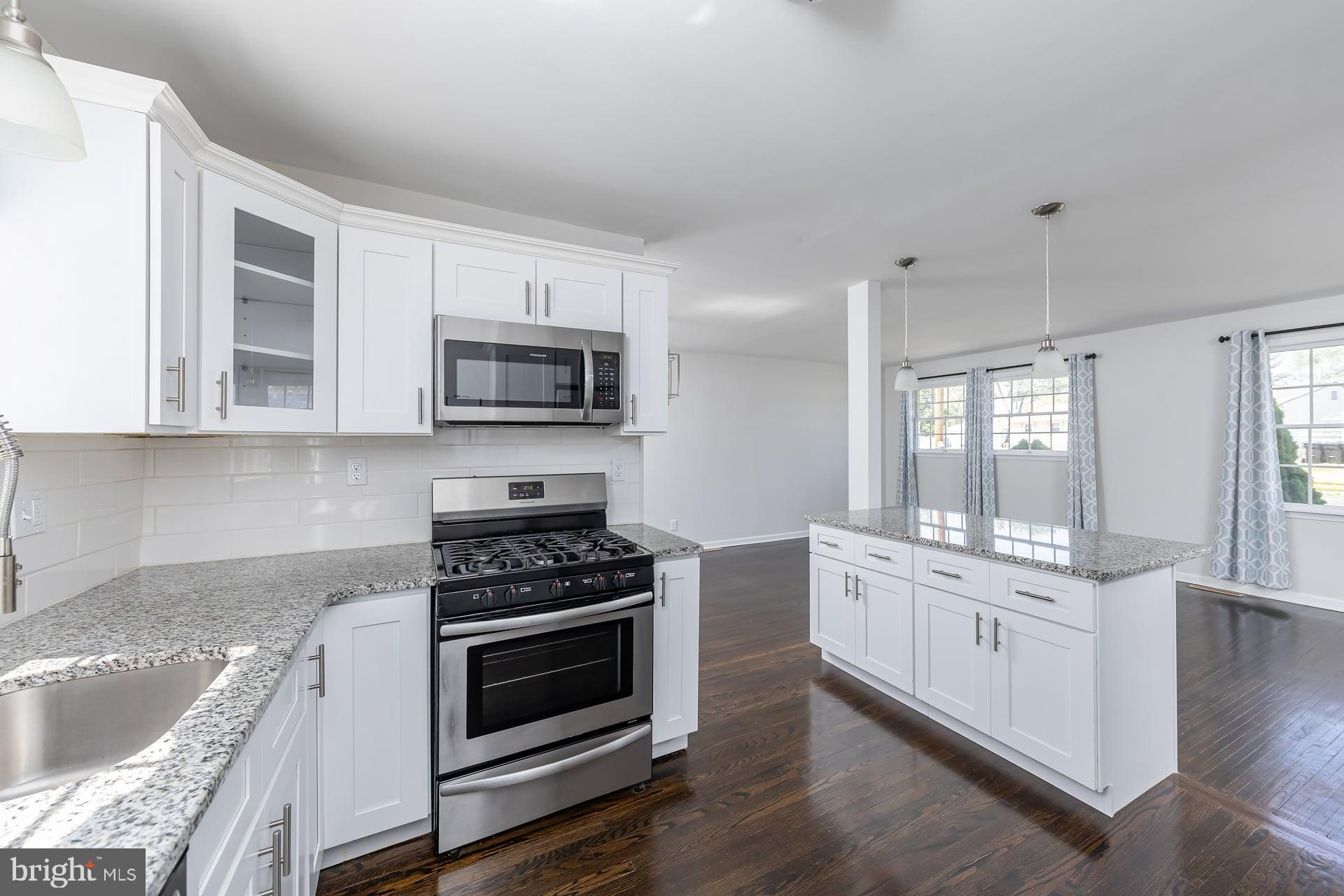 1203 Cedar Drive Pine Hill, NJ 08021 - Photo 5 of 19 a kitchen with granite countertop a stove top oven a sink dishwasher and white cabinets with wooden floor