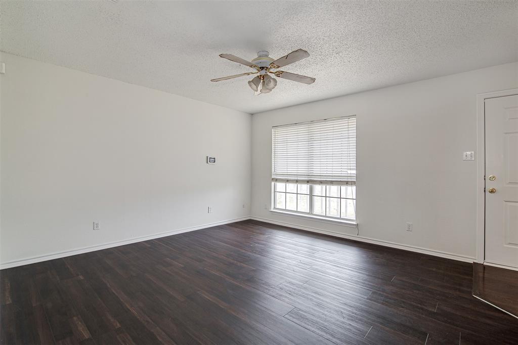 606 McAnear Street Cleburne, TX 76033 - Photo 3 of 19 an empty room with wooden floor fan and windows