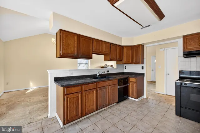 a kitchen with granite countertop a sink cabinets and stainless steel appliances