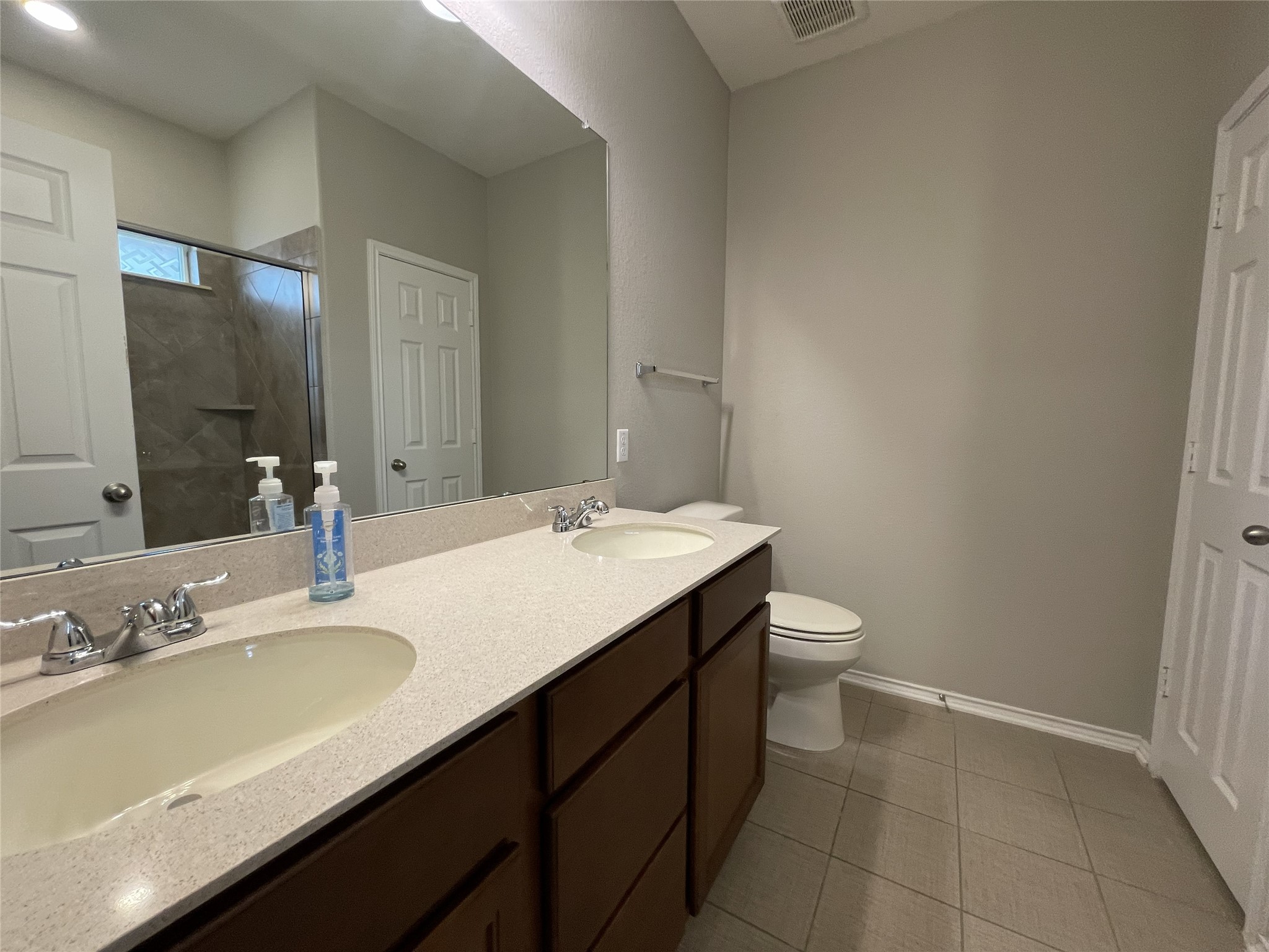 2471 Sunrise Road, Unit 62 Round Rock, TX 78664 - Photo 14 of 28 Full bathroom featuring a shower stall, double vanity, and dark tile patterned flooring